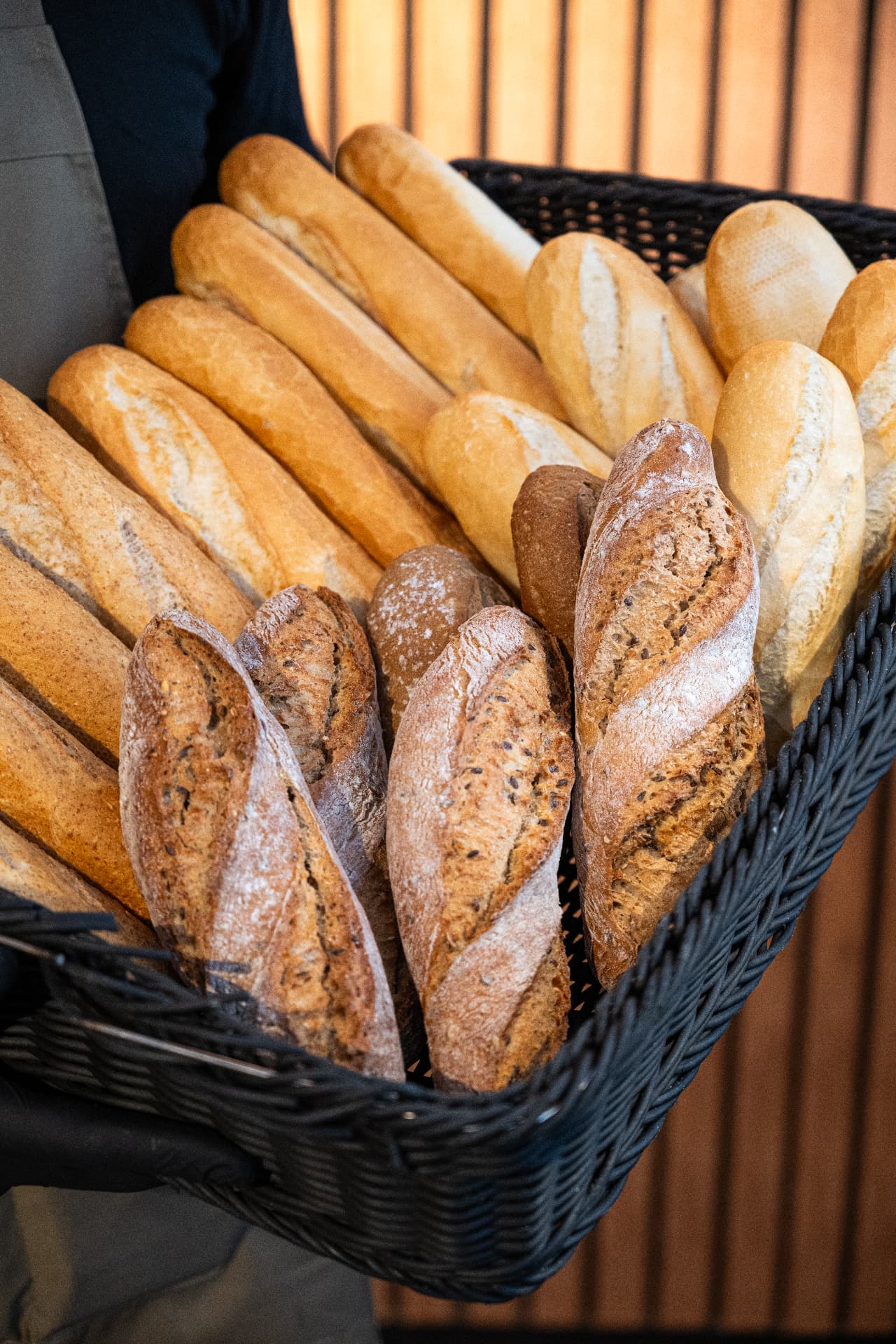 Mand met vers brood: witte en meergranen pistolets en stokbroden bij RAAM Amsterdam